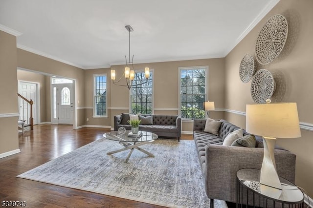 living area with an inviting chandelier, crown molding, baseboards, and wood finished floors