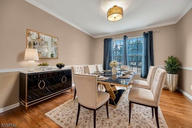 dining area with baseboards, ornamental molding, and wood finished floors