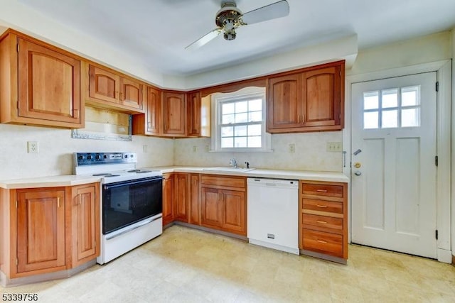 kitchen featuring brown cabinetry, white appliances, light countertops, and a sink