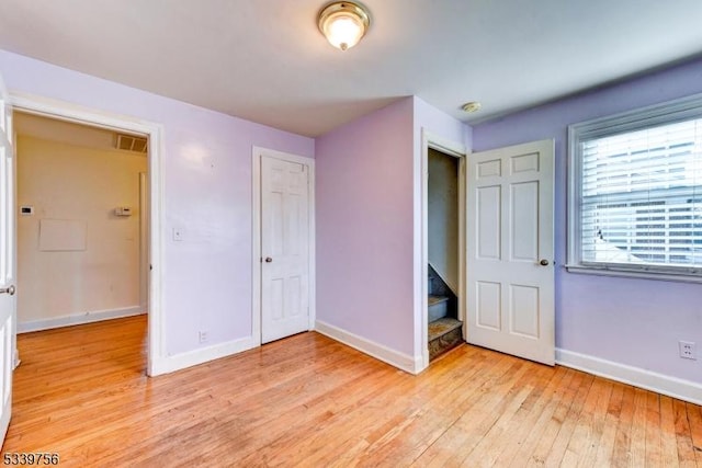 unfurnished bedroom featuring light wood-style floors, visible vents, baseboards, and a closet