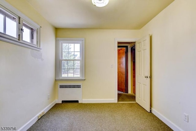 spare room with baseboards, carpet flooring, and radiator heating unit