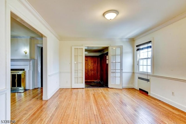 foyer featuring a fireplace, ornamental molding, french doors, light wood-type flooring, and radiator