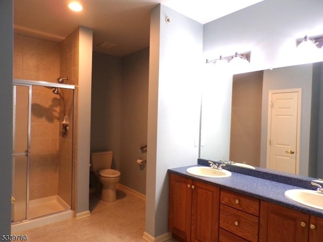 bathroom featuring a stall shower, a sink, toilet, and double vanity