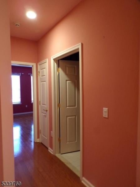 corridor featuring baseboards and wood finished floors