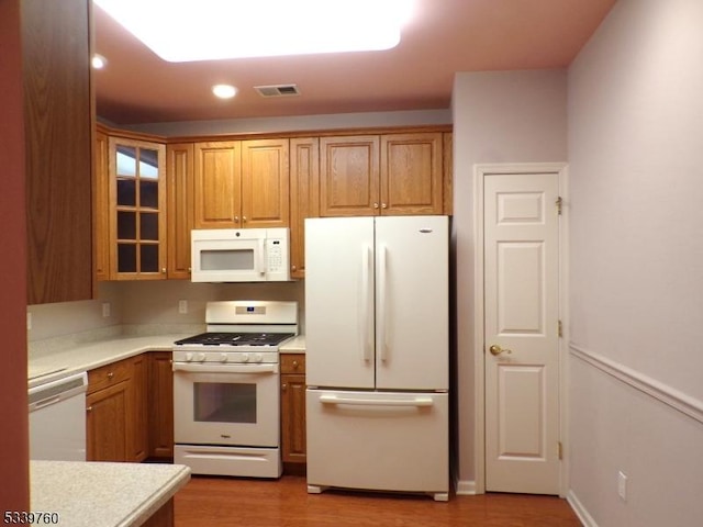 kitchen featuring brown cabinets, white appliances, and light countertops