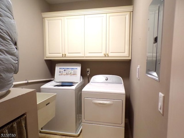 clothes washing area featuring washing machine and dryer, electric panel, and cabinet space