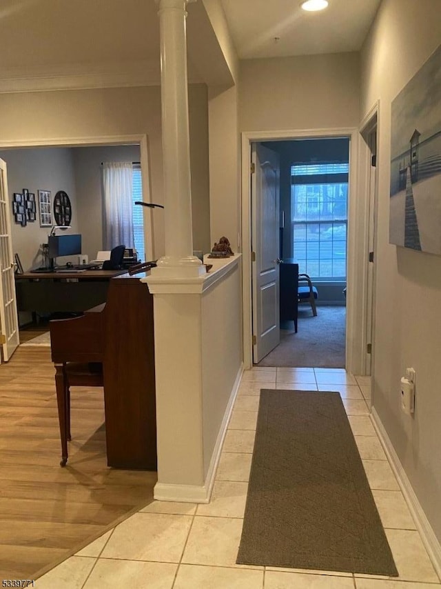 corridor featuring decorative columns, baseboards, and light tile patterned floors