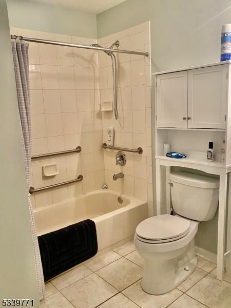 bathroom featuring tile patterned flooring, shower / bathtub combination with curtain, and toilet