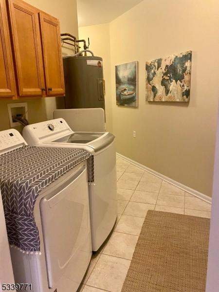 laundry area featuring water heater, cabinet space, washing machine and clothes dryer, and light tile patterned flooring