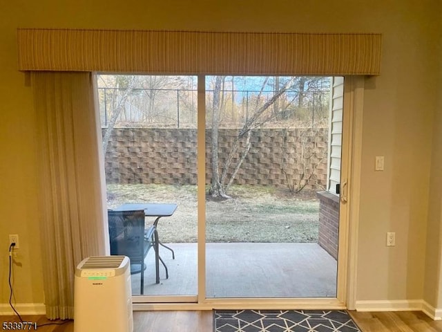 doorway to outside with a wealth of natural light, baseboards, and wood finished floors