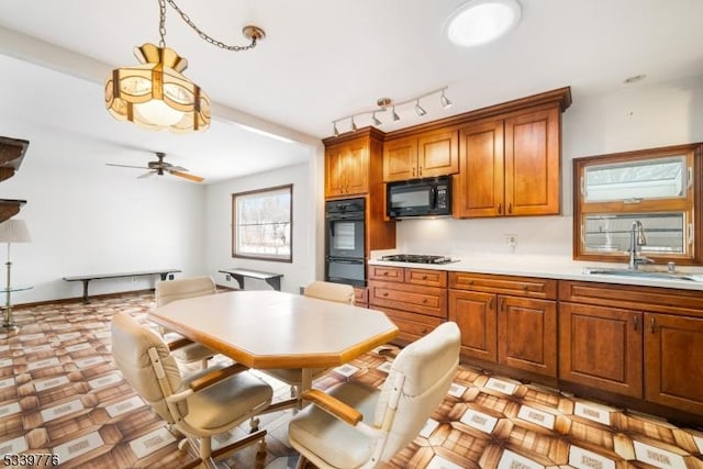 kitchen with brown cabinets, light countertops, a sink, ceiling fan, and black appliances