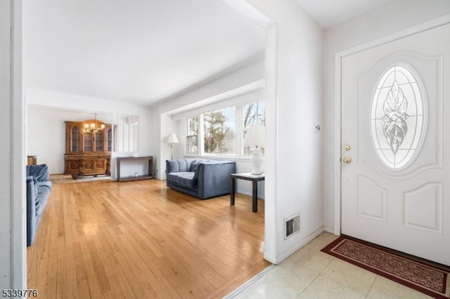 entryway featuring wood finished floors, visible vents, and an inviting chandelier