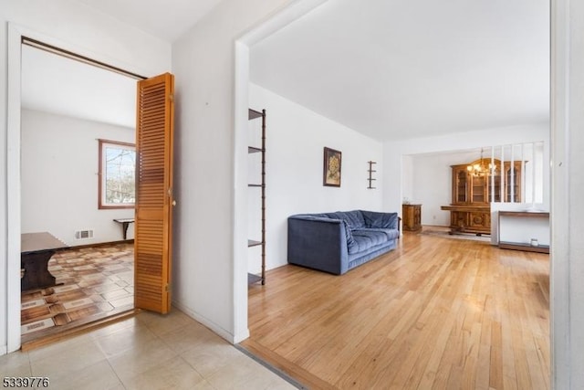 unfurnished living room featuring wood finished floors, visible vents, and an inviting chandelier