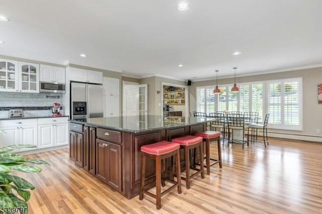 kitchen featuring decorative light fixtures, stainless steel appliances, white cabinetry, decorative backsplash, and glass insert cabinets