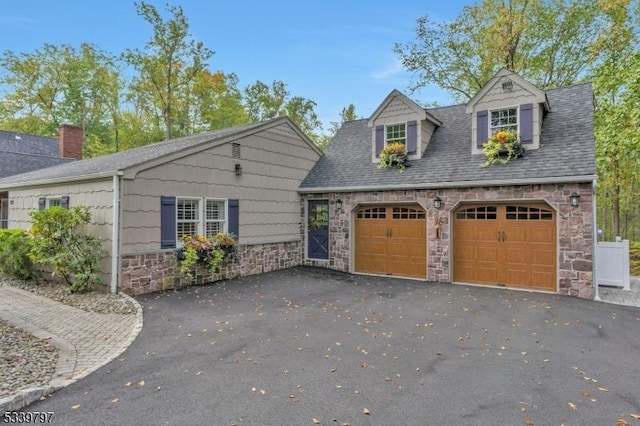 view of front of house featuring a garage, stone siding, roof with shingles, and driveway