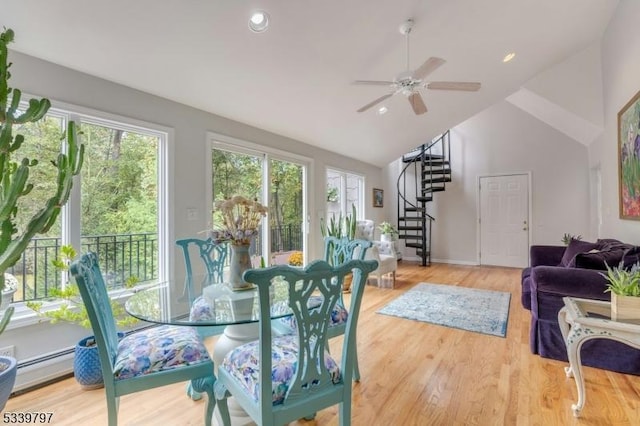 dining space featuring a baseboard radiator, wood finished floors, a healthy amount of sunlight, and stairs