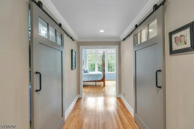 doorway with baseboards, a barn door, light wood-type flooring, and crown molding