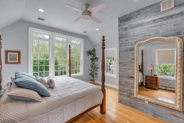 bedroom featuring a baseboard radiator, visible vents, vaulted ceiling, and wood finished floors