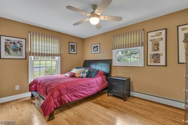 bedroom with a ceiling fan, baseboards, baseboard heating, and wood finished floors