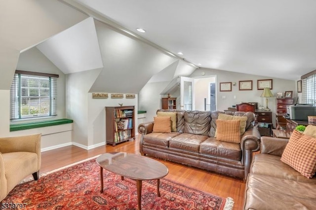 living area featuring lofted ceiling, wood finished floors, and baseboards