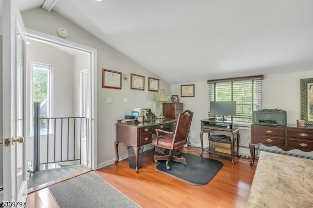 office space featuring lofted ceiling with beams, wood finished floors, a wealth of natural light, and baseboards