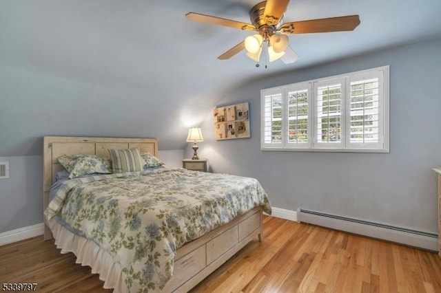 bedroom featuring light wood-type flooring, a baseboard radiator, and baseboards