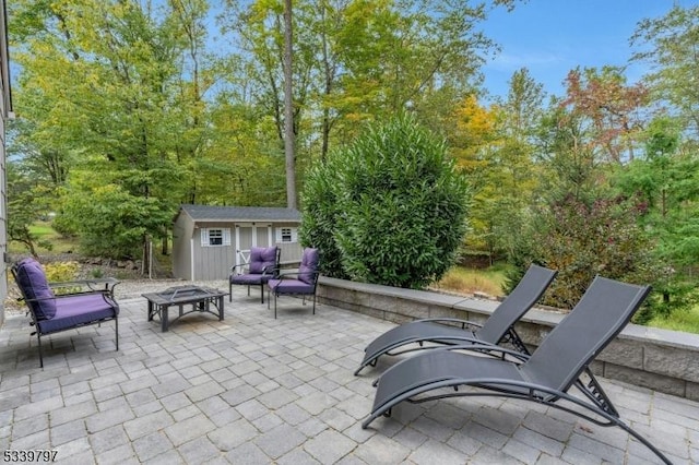 view of patio featuring an outdoor living space with a fire pit, a shed, and an outbuilding