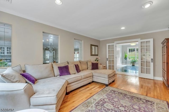 living room with light wood-style floors, a wealth of natural light, crown molding, and french doors