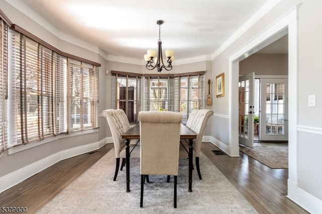 dining space with an inviting chandelier, baseboards, and wood finished floors