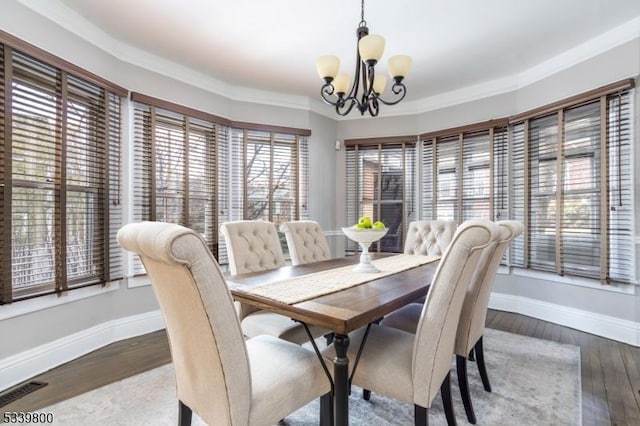 dining space with a chandelier, crown molding, baseboards, and wood finished floors