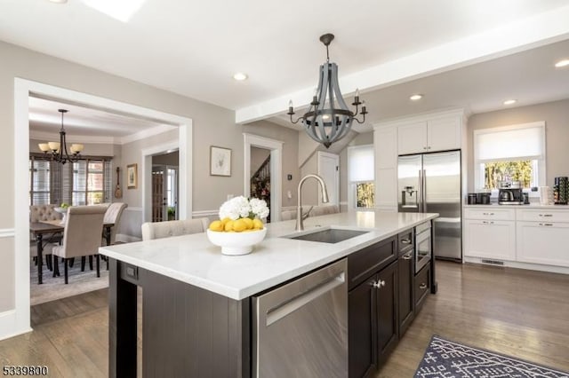 kitchen featuring appliances with stainless steel finishes, a healthy amount of sunlight, a sink, and an inviting chandelier