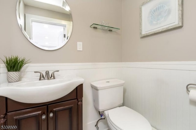 bathroom with wainscoting, vanity, and toilet