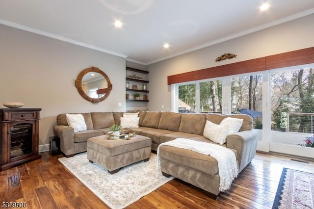 living area with dark wood-type flooring, visible vents, and crown molding