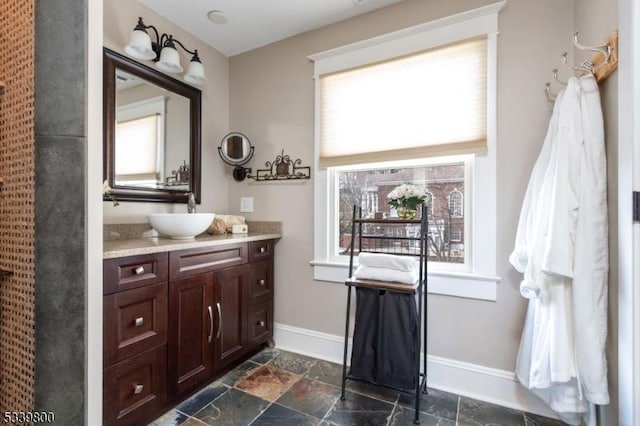 bathroom with baseboards, vanity, and stone tile floors