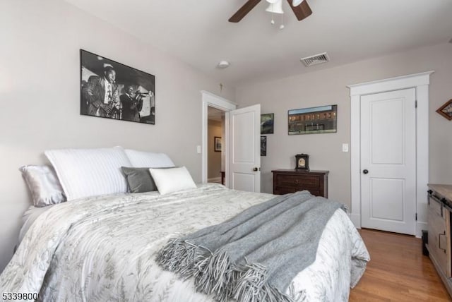 bedroom with a ceiling fan, visible vents, and wood finished floors