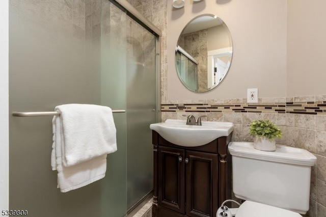 bathroom with toilet, a shower stall, tile walls, and vanity