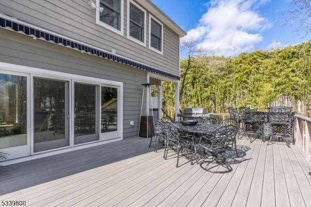 wooden terrace with a grill and outdoor dining area