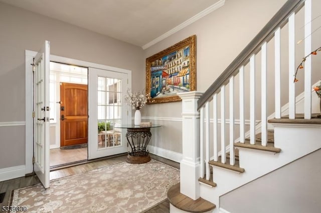 foyer entrance with crown molding, stairs, baseboards, and wood finished floors