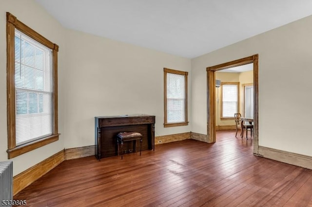 unfurnished living room with radiator, a fireplace, baseboards, and hardwood / wood-style flooring