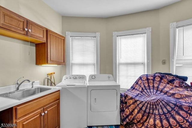 laundry room with washing machine and dryer, cabinet space, and a sink