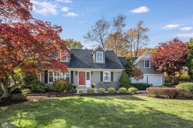 new england style home featuring a garage, a front yard, and a shingled roof