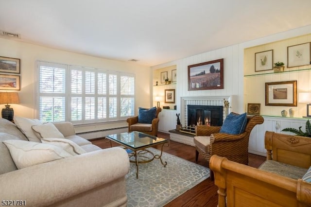 living room with a baseboard radiator, a brick fireplace, visible vents, and dark wood-style flooring