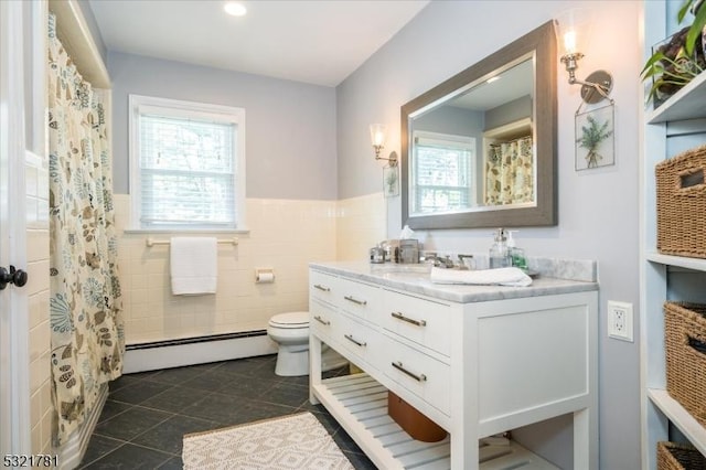 full bathroom with toilet, tile patterned flooring, vanity, a baseboard heating unit, and tile walls