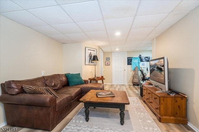 living room with light wood-type flooring, baseboards, and a drop ceiling