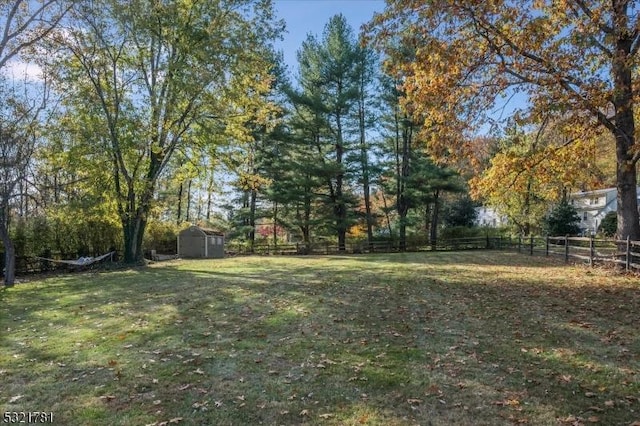 view of yard featuring fence, an outdoor structure, and a storage unit