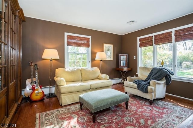 living area featuring a baseboard heating unit, visible vents, and wood finished floors