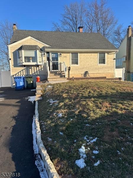 view of front of home featuring aphalt driveway, roof with shingles, and a chimney