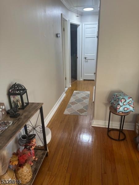 hall with attic access, crown molding, baseboards, and wood finished floors