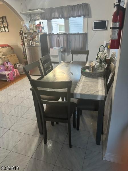 dining room with arched walkways and tile patterned floors