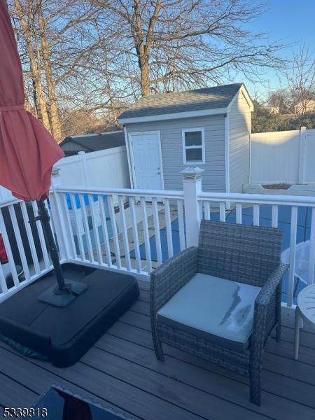 wooden deck featuring an outdoor structure, a storage shed, and fence